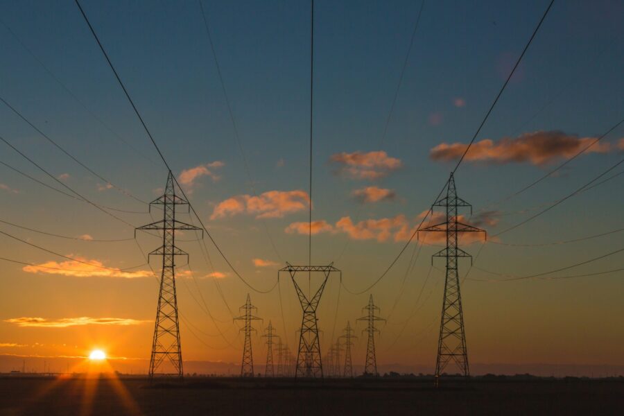Electricity pylons and power lines silhouetted against a setting sun