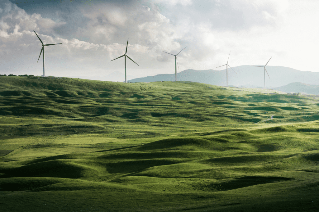 Wind turbines on rolling green hills under a cloudy sky