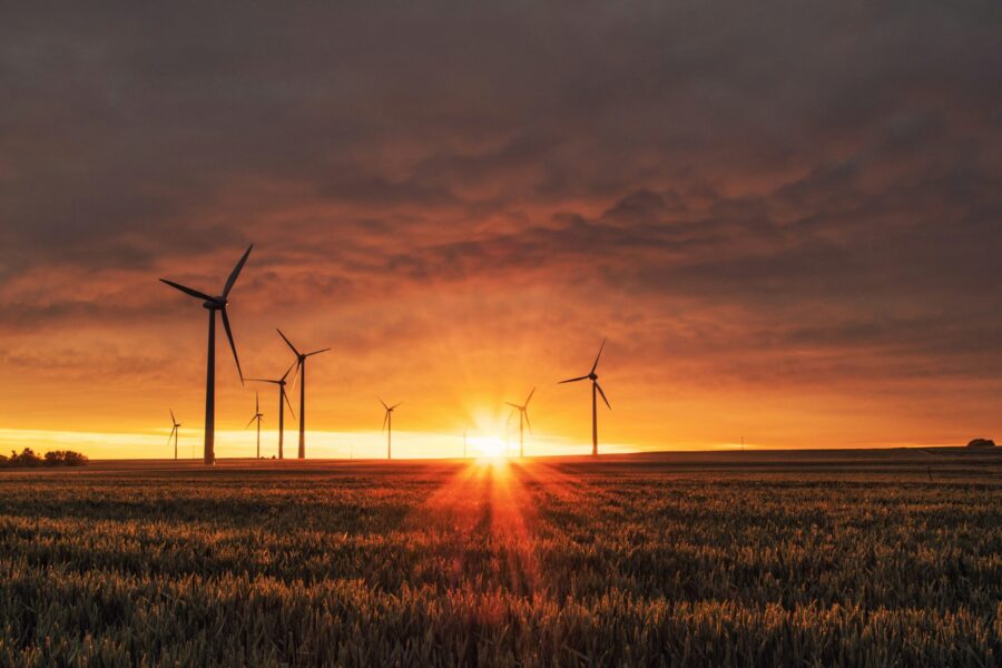 Wind turbines in a field silhouetted against a glowing sunset