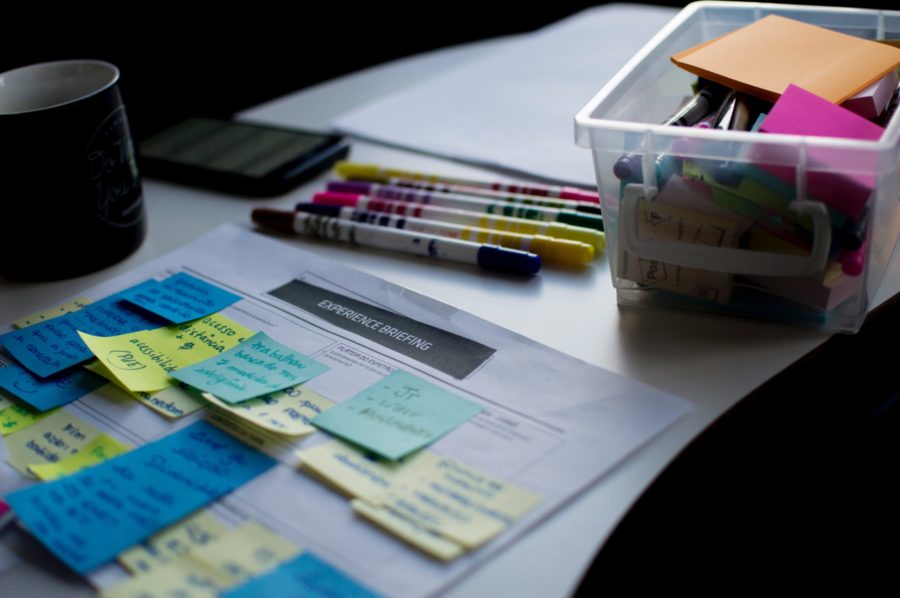 Coloured sticky notes on an experience briefing sheet beside marker pens