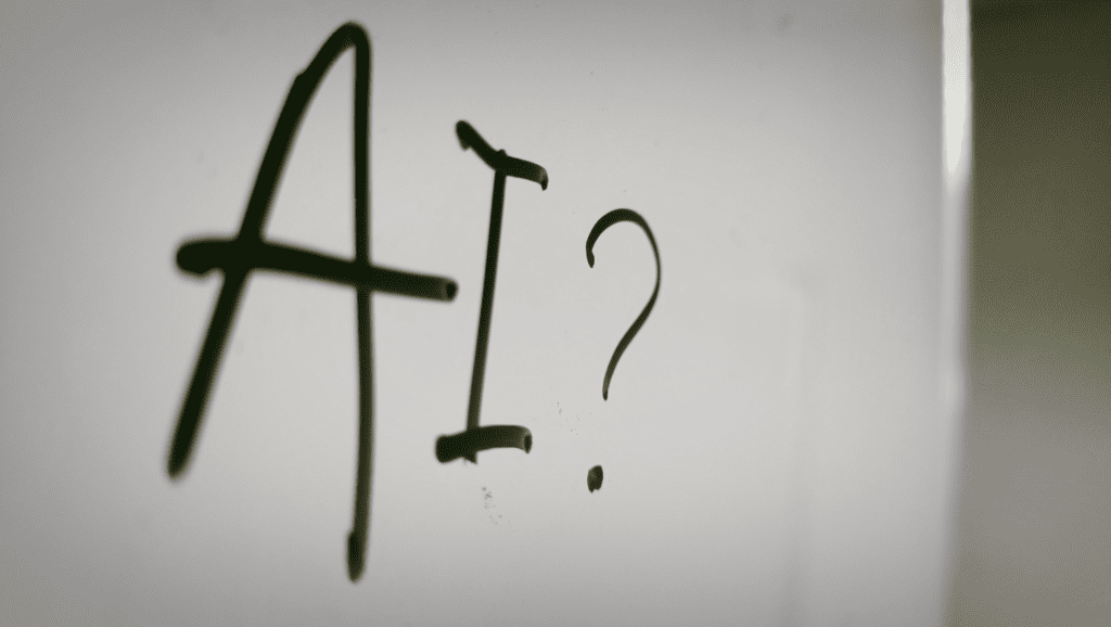 Handwritten "AI?" on a white wall