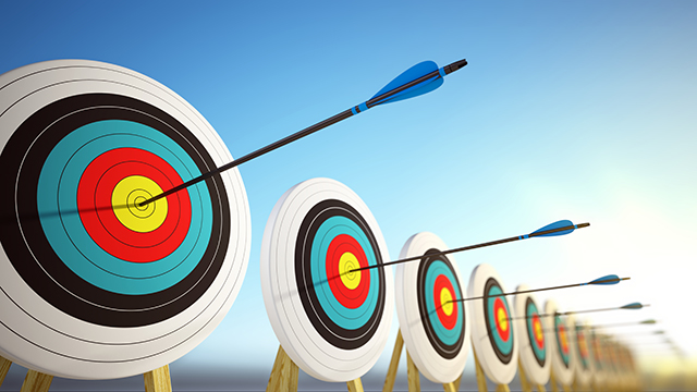 Arrows hitting the bullseye of a row of archery targets